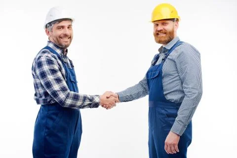 Two engineers shake hands on a white background Stock Photos
