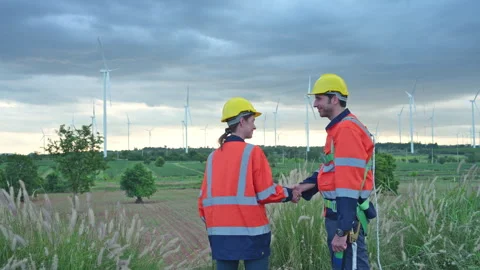 Two engineers shaking hands on the background of wind turbines Video stock 254000368