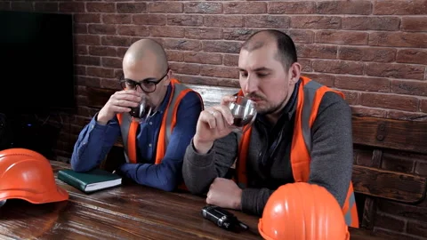Two engineers sit at the table and drink coffee, chat, make notes Stock Footage 103492415