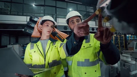 Two engineers stand beside an orange robotic arm Stock Footage 340982814