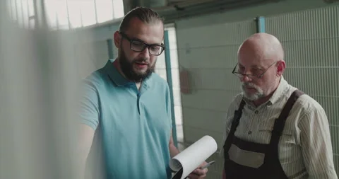 Two engineers stand at factory facility use materials and examine machines Stock-Footage 130559412