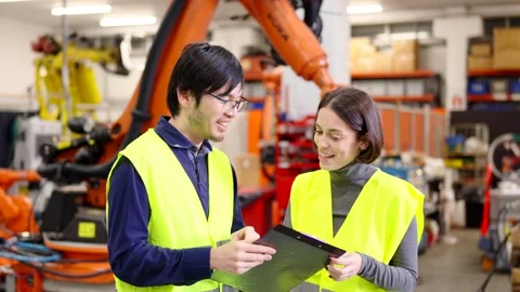 Two engineers talking while robot working behind Stock Footage 258805465