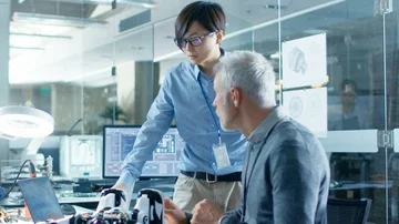 Two Engineers Talking while Working with Robot, Checking Data on Laptop Computer Stock Footage 85770817