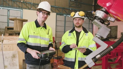 Two engineers test and control robotic arm in mechanical manufacturing factory. Stock Footage 226223269