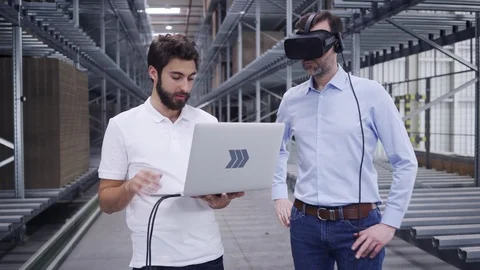 Two engineers testing virtual reality in factory warehouse with VR goggles an Stock Footage 108459570