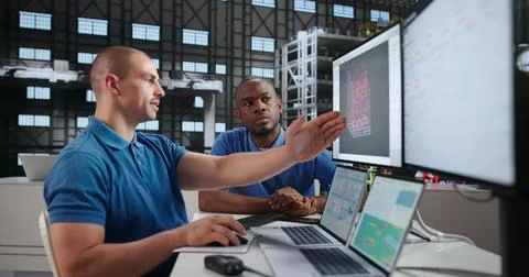 Two Engineers Using Laptops To Design Rockets In Aerospace Lab. Stock Photos