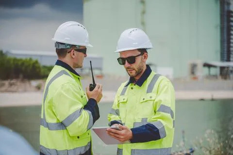 Two engineers using radio and tablet at coastal oil gas facility in safety .. Foto stock