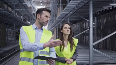 Two engineers walking through factory with tablet and talking Stock Footage 108457994