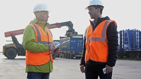 Two engineers wearing hardhats talking together while standing on a large Stock Footage 101232307