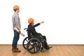 The two engineers with a wheelchair gesture on the white wall background Photo
