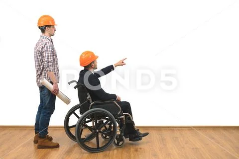 The two engineers with a wheelchair gesture on the white wall background Stock Photos