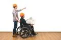 The two engineers with a wheelchair gesture on the white wall background Photo