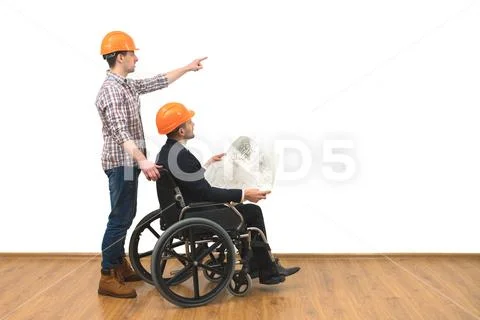 The two engineers with a wheelchair gesture on the white wall background Stock Photos
