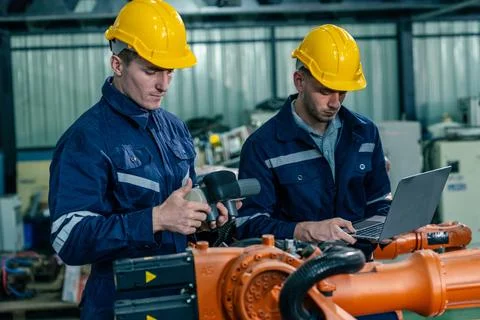 Two engineers work together in a manufacturing facility, focusing on techno.. Stock Photos
