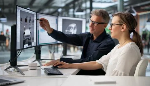 Two Engineers Working On Computer To Develop Car Gearbox Design. Foto stock