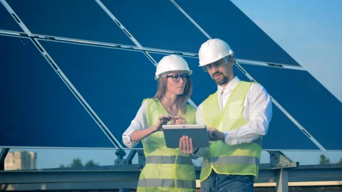 Two engineers working near solar panels on a building roof. Renewable energy Stock Footage 96209610