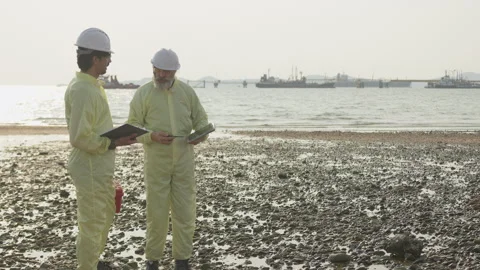 Two environmental engineers conduct a site inspection on a rocky shoreline Stock Footage 335701302