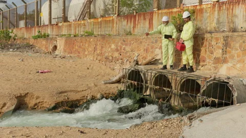 Two environmental scientists in hazmat suits inspect a sewer outfall Vídeo Stock 346079947
