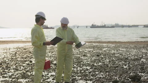 Two environmental scientists in protective gear perform a coastal site Stock Footage 338294052