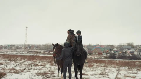 Two equestrians training their horses on winter terrain. Pair of riders learning Stock Footage 345178000