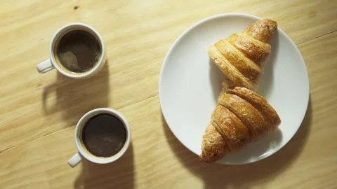 Two espresso cups and croissant in morning sun rays Stock Footage 317674846