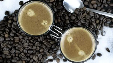 Two Espressos in a bed of coffee beans and sugar Stock Photos
