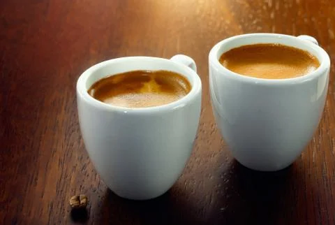 Two espressos with a single coffee bean Stock Photos