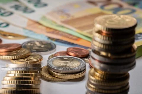 Two Euro coin in focus, stack of Euro coins. Banknotes in the background Stock Photos