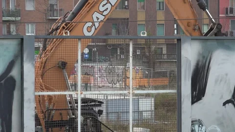 Two Excavator Arm moving Behind a Rusty Fence in Urban Area - C0017 Stock Footage 292641106