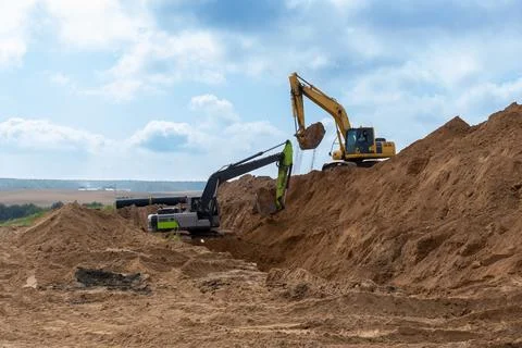 Two excavators move soil at a construction site Stock Photos