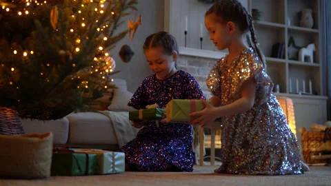 Two excited girls taking gift box under Christmas Tree sitting on the floor. Stock Footage 201248641