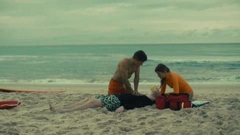 Two experienced Lifeguards performing CPR on the beach and giving oxygen Stock Footage 263917186