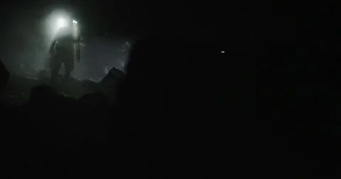 Two explorers walking into a dark smoky cave with headlamps in slow motion Stock Footage 64681336