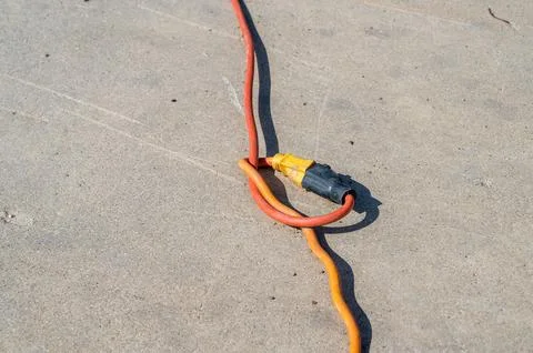 Two extension cords plugged into each other with a knot on a cement background Stock Photos
