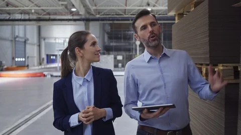 Two factory floor managers discussing work while walking and looking at table Stock Footage 108445538