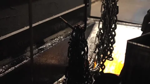 Two factory workers examine a heap of finished chain links on a dark workbench Stock Footage 339124706