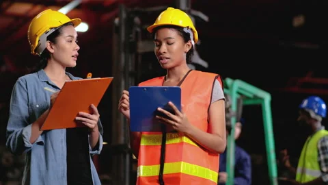 Two factory workers or technician hold clipboard and discuss with co-worker Stock-Footage 142629095