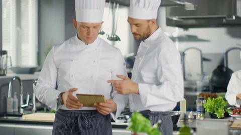 Two Famous Chefs Exchange Ideas About Video Blog Recipe they Watching on Tablet. Vidéo 77020342
