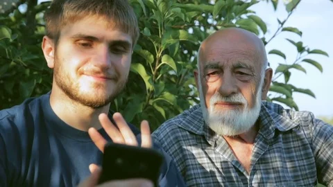 Two farmers are holding a videoconference with a smartphone sitting in an Stockbeeldmateriaal 78786190