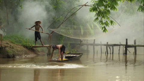 Two farmers on a boat in the river using a fishnet to catch fish Video stock 311294912