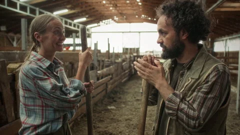 Two Farmers Leaning on Tools and Chatting during Break in Barn Video stock 342035359