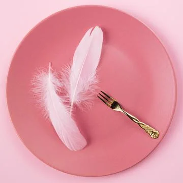 Two feathers in the pink plate with gold fork. Minimal love concept Stock Photos