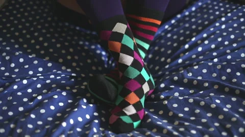 Two feet with different socks and unpaired move one on the other, on the sofa Stock-Footage 55630158