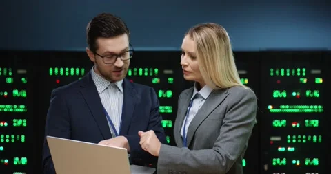 Two fellow programmers stand in server room and discuss work tasks. Male Stock Footage 152056264