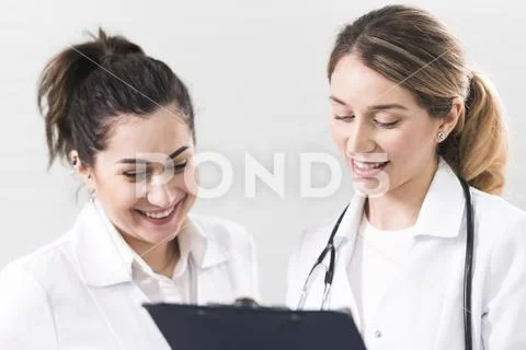 Two female assistants dressed in white coats talking to each other in the den Stock Photos