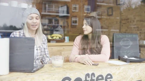 Two female business executives using laptop and talking in coffee shop Stock Footage 107999903