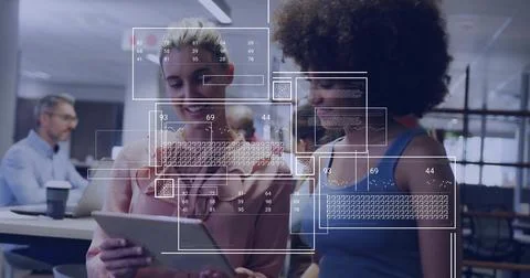 Two female colleagues reviewing code on tablet in open-plan office, with UI 스톡 사진