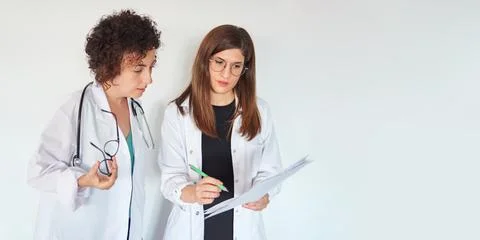 Two female doctors look at documents and discuss a diagnosis Foto stock