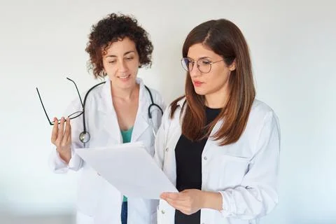 Two female doctors look at documents and discuss a diagnosis Stock Photos