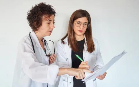 Two female doctors look at documents and discuss a diagnosis Stock Photos